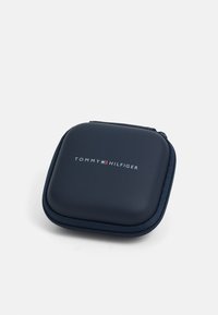 Mørkeblå firkantet glidelås etui med avrundede kanter, merket med Tommy Hilfiger-logoen og flagget i sentrum på hvit bakgrunn.