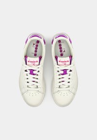 Hvite lær sneakers med lilla detaljer, featuring perforert tå, flate snørebånd, og logo på tungen og innersålen.