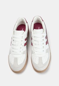 White sneakers with maroon accents, featuring a smooth leather upper, perforated toe, gum sole, and flat white laces.