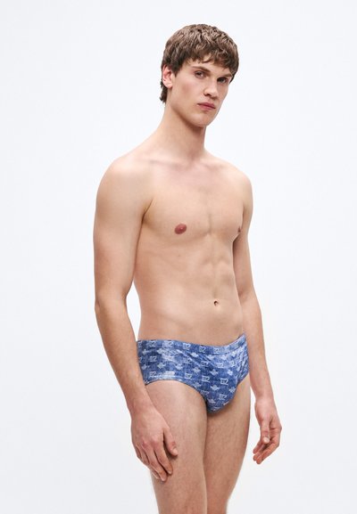 Bañador corto de hombre en azul, con un diseño texturizado en tonos azul claro y oscuro. El material parece liso y ajustado.