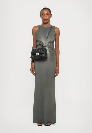 Graues ärmelloses Maxikleid mit einem Knoten-Detail in der Taille; das Model hält eine strukturierte schwarze Handtasche mit einem gebogenen Griff und silbernen Beschlägen.