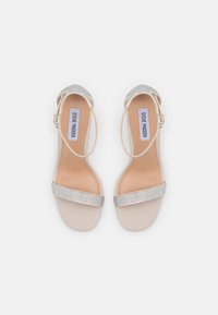 Nude hælede sandaler med en skinnende sølvrem, åben tå-design og justerbar ankelrem, der har en glat tekstur og logo indersål.