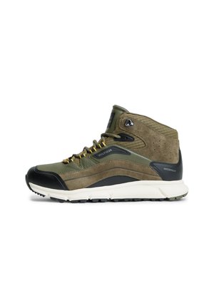Wysokie buty trekkingowe w zielono-brązowym kolorze z czarnym czubkiem, białą podeszwą, żółtymi sznurowadłami oraz wodoodporną metką na pięcie.