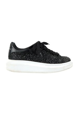 Baskets noires pailletées avec une semelle blanche épaisse, des lacets noirs et un renfort de talon noir lisse.