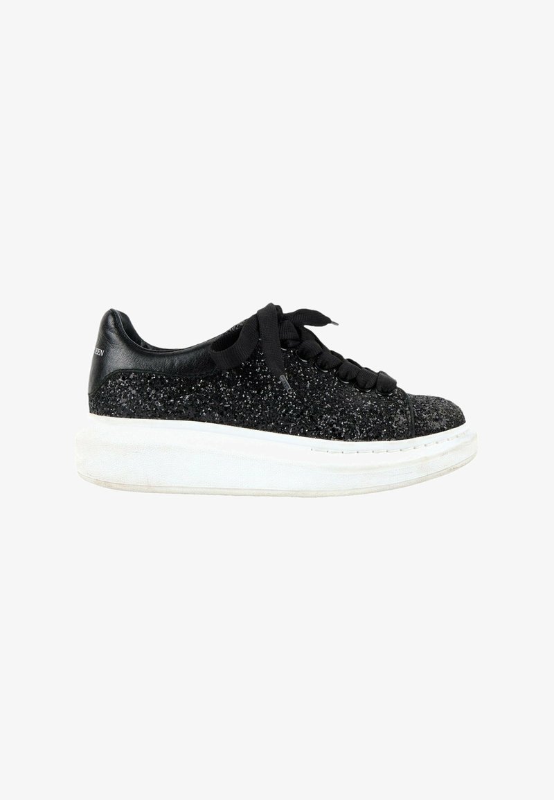 Baskets noires pailletées avec une semelle blanche épaisse, des lacets noirs et un renfort de talon noir lisse.