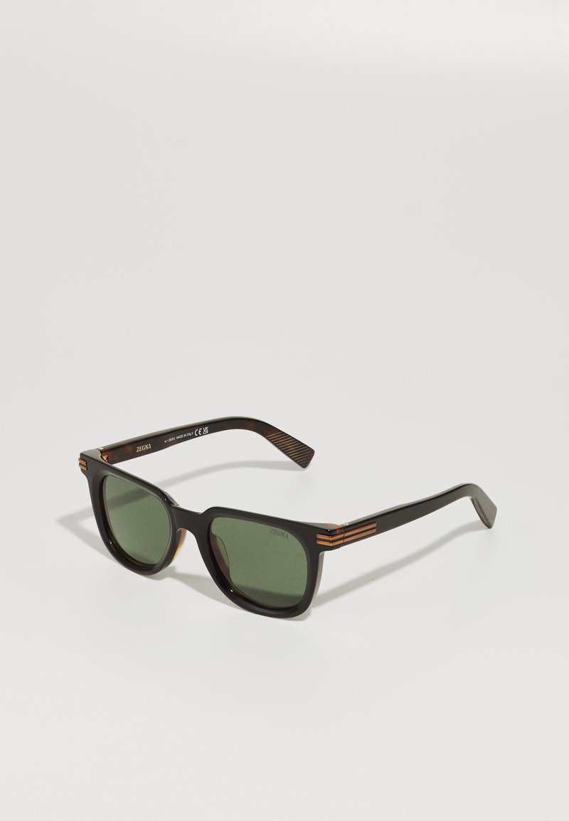 Black square-frame sunglasses with green lenses. Features gold accents on the temples and a matte texture on the arms.