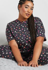 Conjunto de ropa de estar en casa de color gris oscuro que incluye una camiseta de manga corta y pantalones, decorados con patrones de estrellas multicolores en rosa, blanco y naranja.