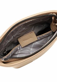 Beige läderpouch med en svart dragkedja. Insidan har grått tyg med ett subtilt mönster och en liten ficka som är sydd inuti.