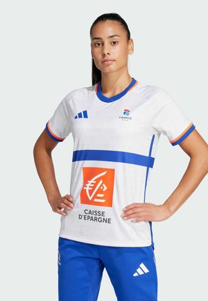 Maglietta sportiva bianca con accenti blu, caratterizzata da una striscia orizzontale blu e il logo dello sponsor. Maniche corte e scollatura rotonda, tessuto texturizzato.