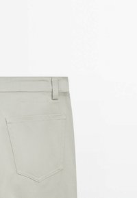 Lichtgrijze denim broek met een gladde textuur, voorzien van een achterzak en een riemlus in de taille, getoond vanaf de achterkant.