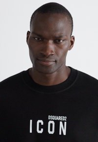 Mustern musta mustern mustern "DSQUARED2 ICON" valge tekstiga. Ümar kaelus, pehme kangas ja minimalistik disain.
