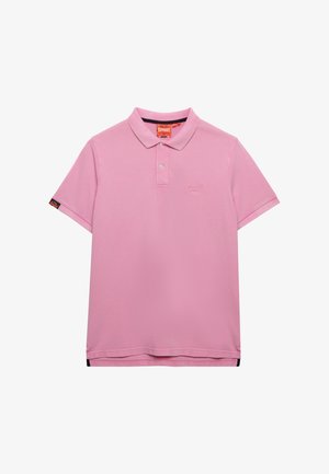 Polo rose uni à manches courtes avec deux boutons blancs, petit logo sur le côté gauche de la poitrine et une étiquette noire et orange sur la manche gauche.