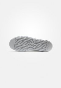 Semelle de sneaker en caoutchouc blanc avec un motif en chevrons. Présente une empreinte de logo et une texture lisse. Bout arrondi et design robuste.