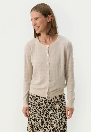 Vaalea beige neulecardigan, jossa on pystysuorat raidat, pyöreä kaula-aukko ja seitsemän pientä napin kiinnitystä. Pehmeä rakenne, vyötärölle istuva.