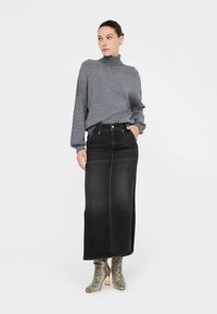 Sivi pleteni džemper s visokim ovratnikom i crna traper midi suknja. Obuća su gležnjače na visoku petu s teksturom zmijskog uzorka. Jednostavan, prilagođeni dizajn.