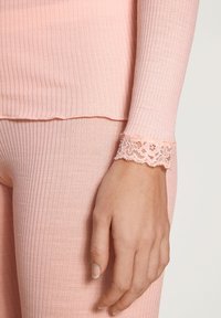 Geribbelde, zachtroze langharige top met een delicate kanten rand bij de pols. De gladde textuur en slim fit verbeteren het algehele ontwerp.
