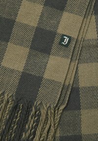 Groene en beige geruite wollen sjaal met gedraaide franjes en een klein donkergroene label met een witte gestileerde letter "J" aan één uiteinde.