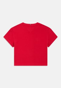 Punainen puuvillapellavainen t-paita pyöreällä pääntiellä ja lyhyillä hihoilla. Takana on V-muotoinen yksityiskohta ja suora helma. Sileä rakenne.