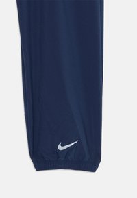 Sötétkék sportnadrág sima anyagból, gumis derékrésszel és passzéval ellátott bokákkal, fehér Nike logóval.