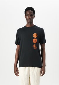 Tricou negru din bumbac cu mâneci scurte, având trei imprimeuri grafice portocalii pe față. Designul include forme geometrice și text.