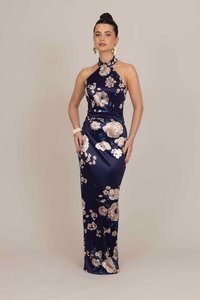 Navy satin evening gown with a halter neckline, floral patterns in cream and blue, form-fitting silhouette, and floor-length design.