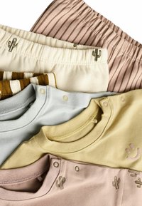 Verschiedene Kinderbekleidung in sanften Pastellfarben: Hellblau, Gelb, Rosa und Creme mit Kaktusmotiven und Druckknöpfen.