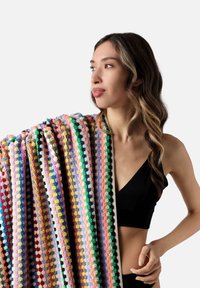 Multicolored crochet blanket featuring round, textured patterns in shades of pink, green, yellow, and red, draped over the shoulder.