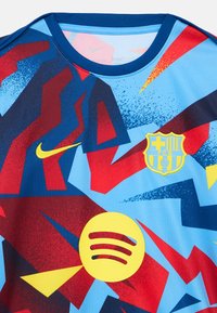 Sinine, punane ja kollane abstraktsete mustritega jalgpallimeeskonna särk FC Barcelona embleemi ning kollaste Nike ja Spotify logodega.