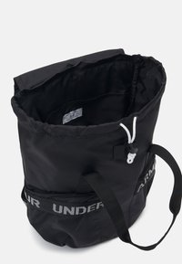 Czarna torba na sznurku z miękkiego nylonu, z mocnymi czarnymi paskami i białym paskiem z logo po boku. Wnętrze w pełni wyłożone.