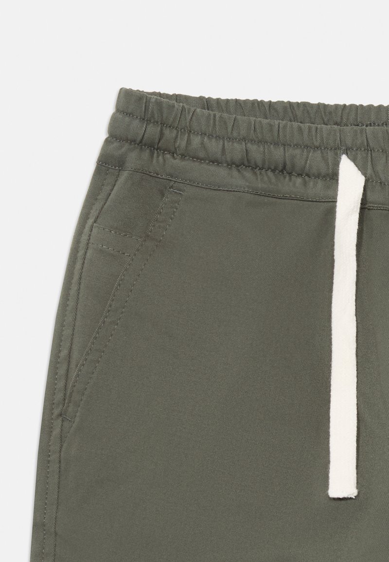 Grüne Jogginghose mit elastischem Bund und einem weißen Kordelzug. Weicher Stoff, Seitentaschen und lockere Passform.