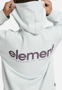 Felpa azzurro chiaro realizzata in morbido tessuto, con un grande logo "element" di colore viola scuro sul retro e una tasca a marsupio davanti.