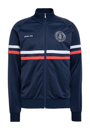 Granatowa kurtka na zamek z białymi i czerwonymi poziomymi paskami, ściągaczami na mankietach i kołnierzu oraz dwoma haftowanymi naszywkami na piersi.