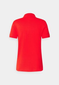 Polo rouge à manches courtes vu de dos avec un col côtelé et un tissu uni sur fond blanc.