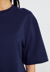Marineblå bomulds t-shirt med korte ærmer, rund hals og et enkelt design. Glat tekstur med minimal syning.