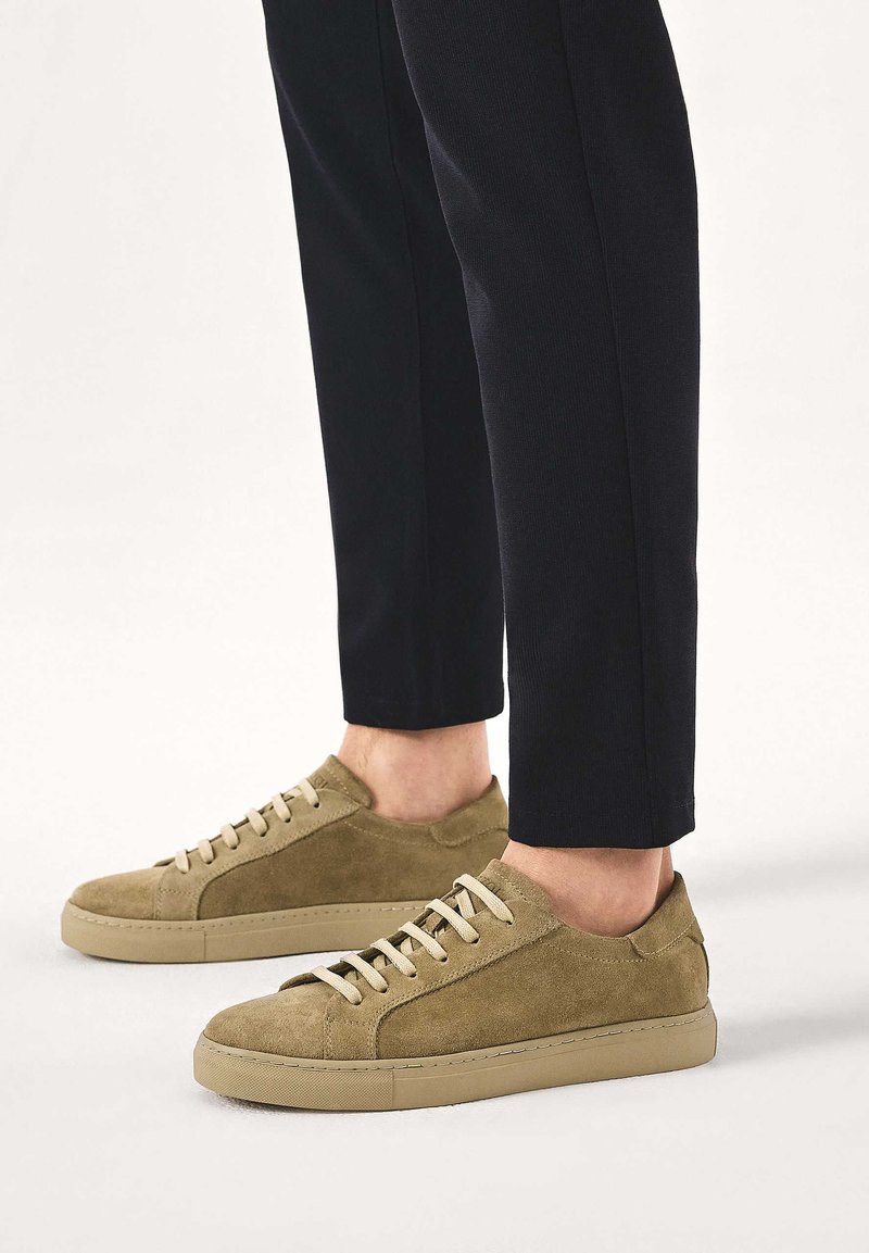 Sametist rohelised tossud beežide paeltega, ümmarguse varbaosaga ja toon-toonis kummist tallaga. Sobitatud kitsaste mustade pükstega.