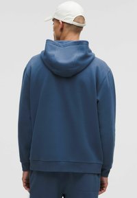 Felpa blu con cappuccio ampio, polsini e orlo a costine. Realizzata in materiale morbido, presenta un design pulito sul retro con accenti minimi.