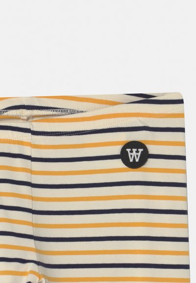 Leggings de algodão leves com riscas horizontais em azul-marinho, amarelo e creme, apresentando um patch circular preto com um logo branco "W".