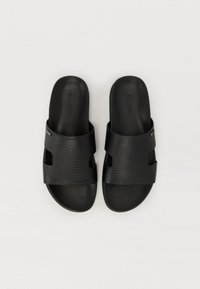 Sandales noires à glissière présentant un dessus texturé, un design ouvert à l'avant et des découpes. Fabriquées en matériau synthétique avec une finition lisse.