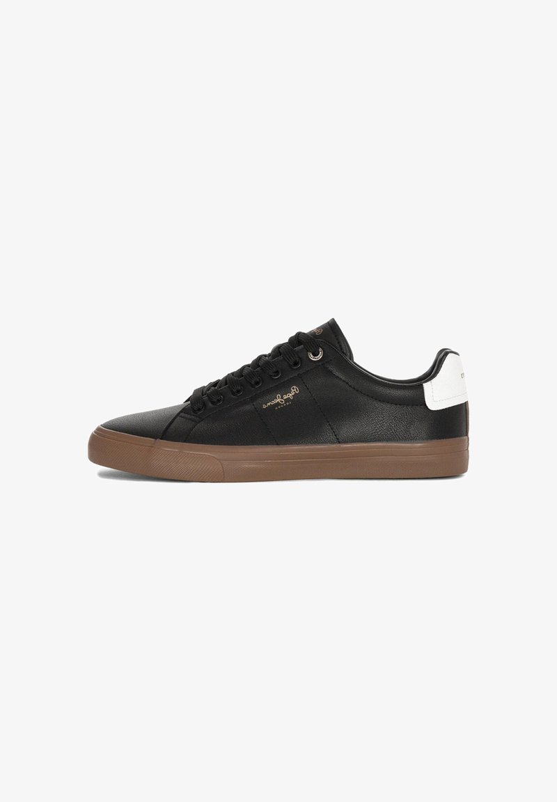 Zapatilla negra de cuero con suela de goma marrón, con cordones negros y un acento blanco en el talón. Textura suave, diseño minimalista.