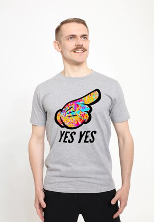 Grå kortærmet t-shirt med en farverig grafik af en pegende hånd og teksten "YES YES" i fed sort skrift.