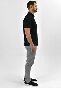 Black polo shirt, gray trousers, and black slip-on shoes. Simple design with short sleeves, smooth texture, and neutral color palette.