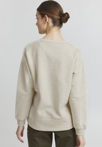 Beige genser med avslappet passform, ribbede mansjetter og rund hals, laget av myk, teksturert stoff. Har detaljer med søm bak.