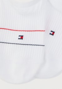 Λευκές ριγωτές κάλτσες μέχρι τον αστράγαλο με λεπτές κόκκινες και ναυτικές ρίγες και ένα μικρό κόκκινο, λευκό και ναυτικό κεντημένο λογότυπο κοντά στα δάχτυλα των ποδιών.