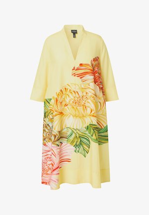 Vestido amarillo con escote en V, mangas tres cuartos y un gran estampado floral multicolor con hojas verdes en el frente y los lados.