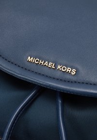 Niebieska skórzana torebka o gładkiej fakturze, z złotymi akcentami. Logo "Michael Kors" wytłoczone na przedniej klapie, z wyłożonym wnętrzem.