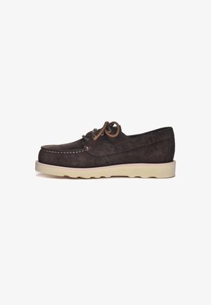 Bateau en cuir suédé marron avec un profil bas, semelle en caoutchouc crème, lacets marron et détails cousus le long des bords.