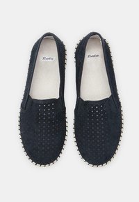 Fekete perforált, slip-on bőrcipők velúrból, fehér fonott talppal és bézs béléssel. Simára csiszolt felülettel és kerek orral rendelkezik.