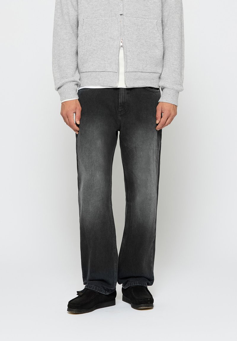 Svart denimjeans med en falmet finish, rett snitt og fem-lomme-design, kombinert med en grå ribbestrikket zip-up genser og svarte slip-on sko.