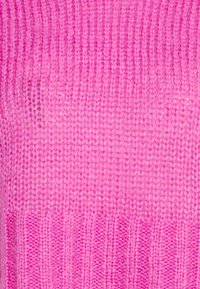 Knit sweater in varying shades of pink, featuring a textured design with vertical ribbing and smooth areas, made of soft yarn.