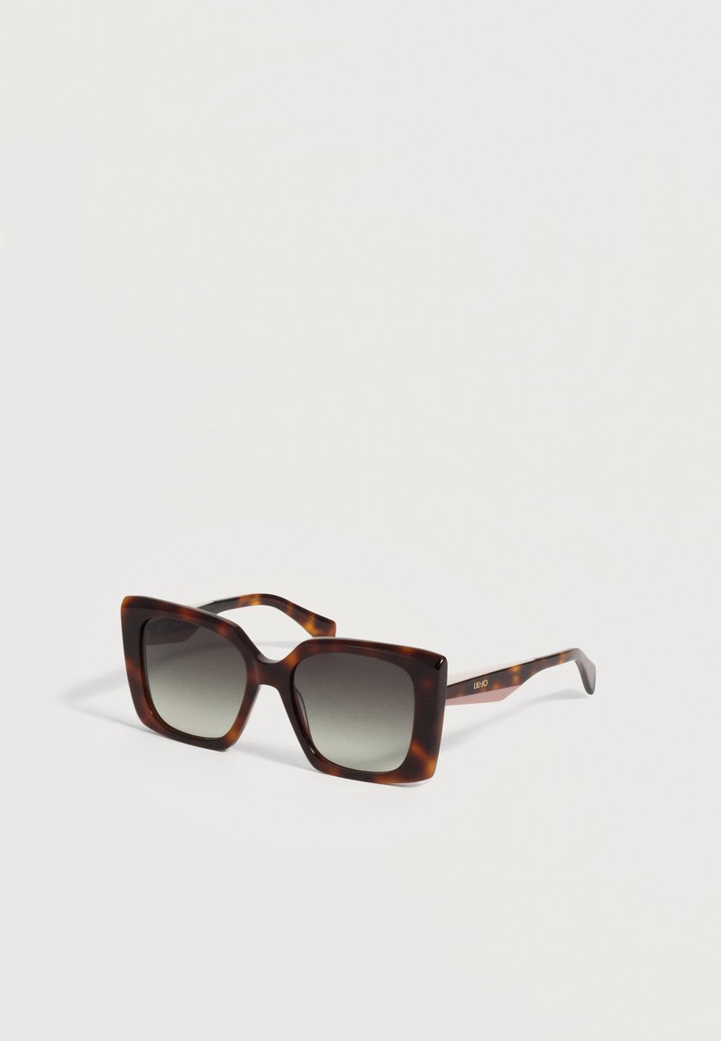 Lunettes de soleil carrées avec verres à dégradé foncé et montures et branches au motif écaille sur fond uni.